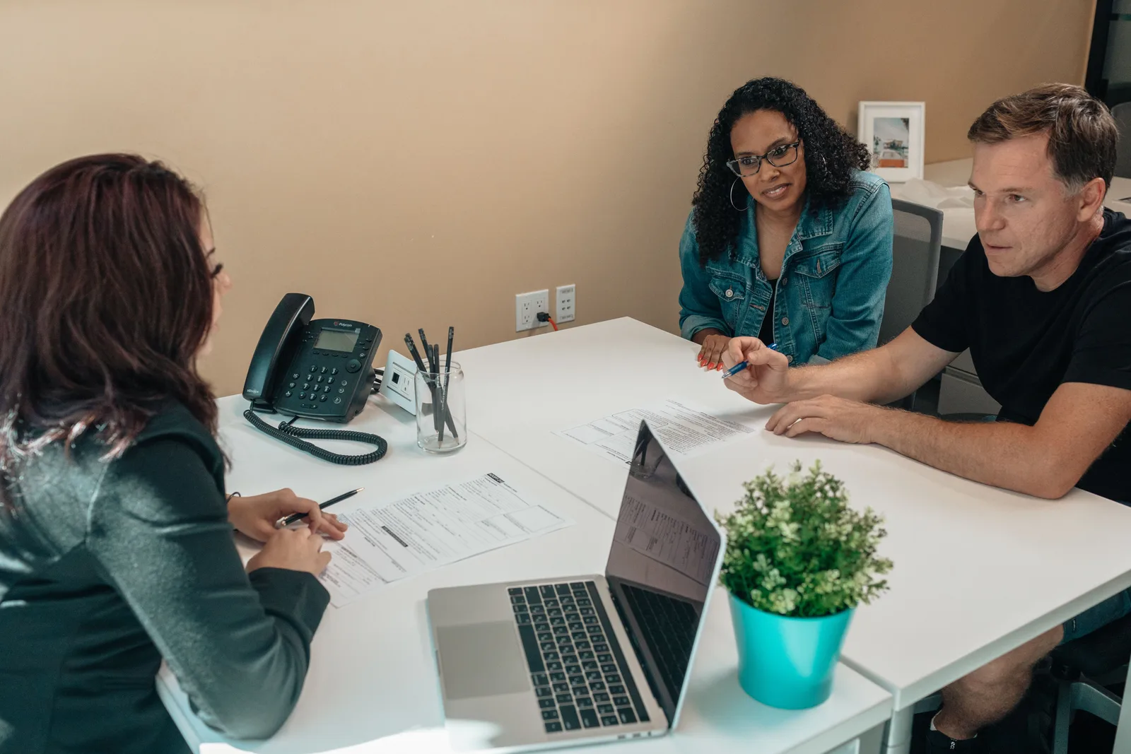 Diverse group engaged in a professional meeting around a desk in an office setting. Studio itinerary building contacts: who to approach
